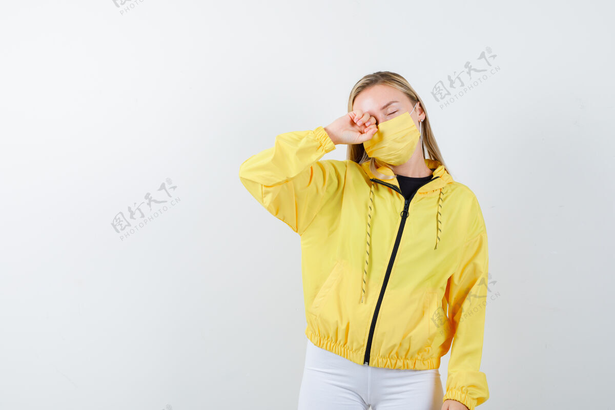 女孩照片中的年轻女士穿着夹克 裤子 面具揉着眼睛 睡意朦胧金发裤子时尚