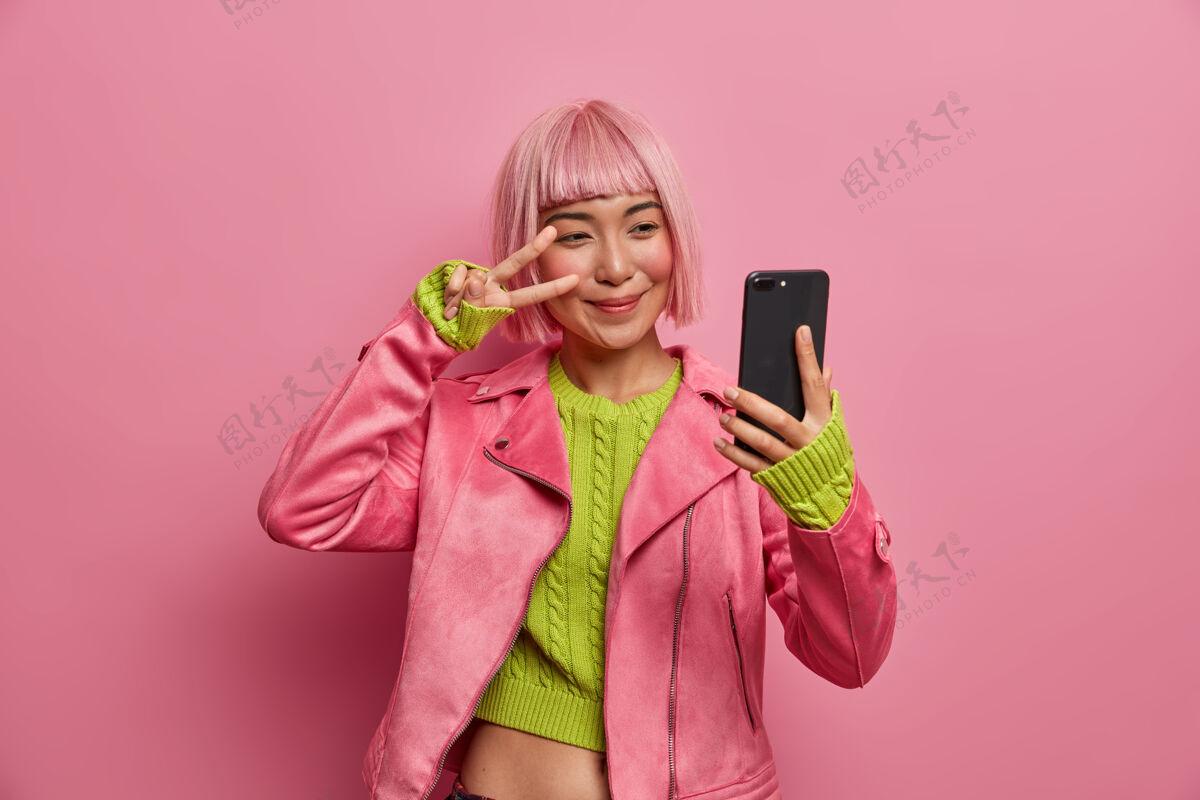 展示快乐时尚的千禧一代女孩展示两个手指在眼睛上 和平标志 自拍 享受她的新发型 染成粉红色的头发视频时尚请