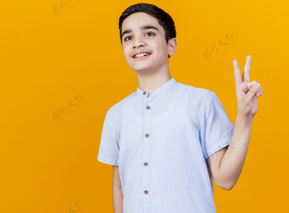 男孩微笑的年轻白人男孩在一旁做和平标志孤立的橙色背景与复制空间侧线橙色年轻