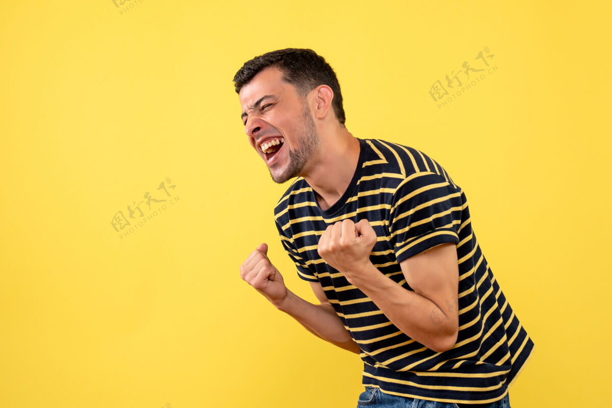 黄正面图：穿着黑白条纹t恤的兴奋帅哥在黄色孤立的背景上展示胜利的姿态黑人获胜者