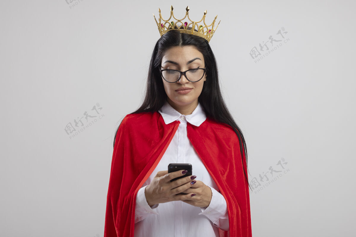 使用高兴的年轻白种人超级英雄女孩戴着眼镜和皇冠用手机隔离在白色背景与复印空间手机电话眼镜