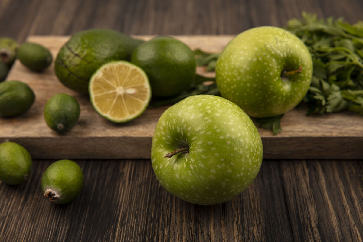 欧芹木制厨房板上健康的绿色苹果的俯视图 木制墙壁上隔离着酸橙 鳄梨和欧芹水果酸橙顶部