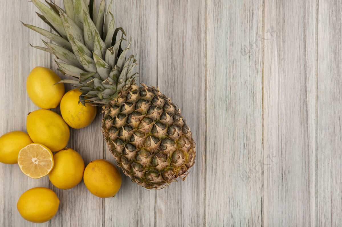 菠萝顶视图新鲜水果 如菠萝和柠檬隔离在一个灰色的木制墙壁与复制空间素食人景观