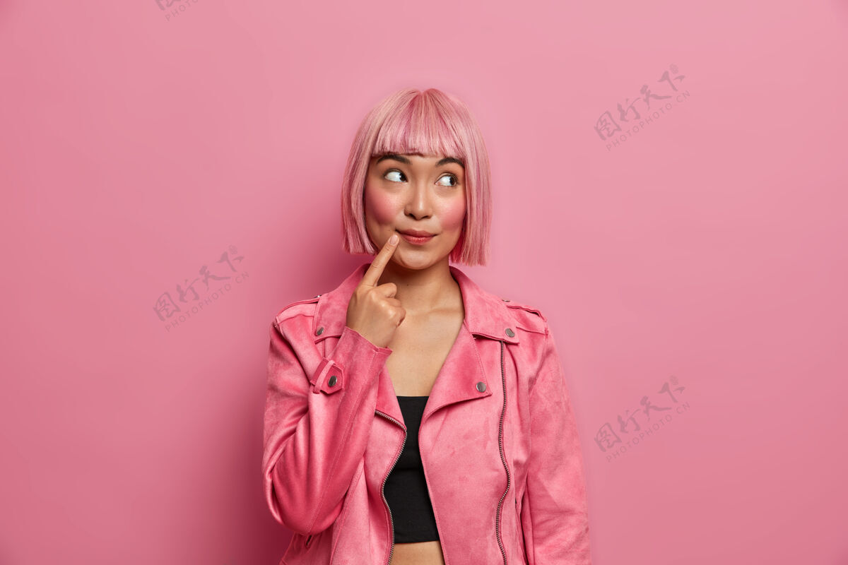 表达美丽梦幻的亚洲女人若有所思的表情移开视线 手指贴着嘴巴 穿着时髦的服装有着时髦的发型粉色的头发年轻粉色发型