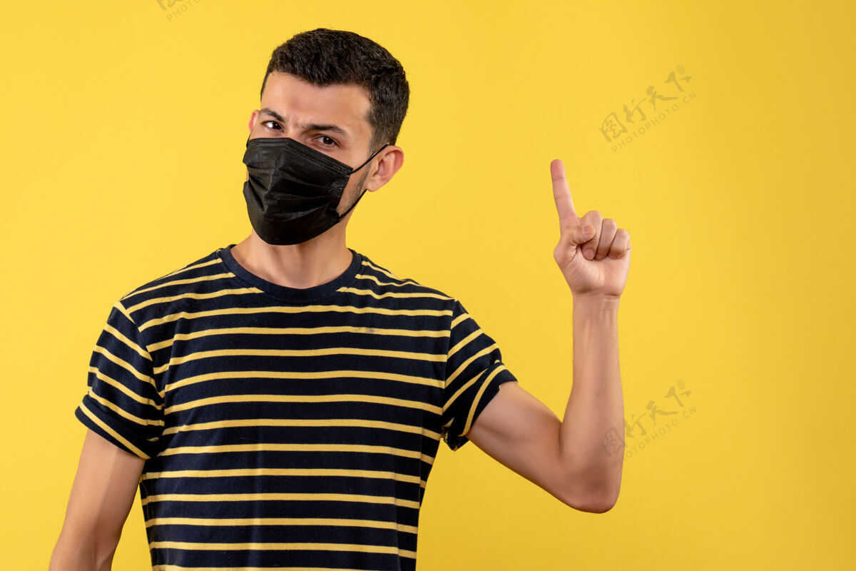 成人正面图穿着黑白条纹t恤的年轻人手指朝上黄色背景男黑向上