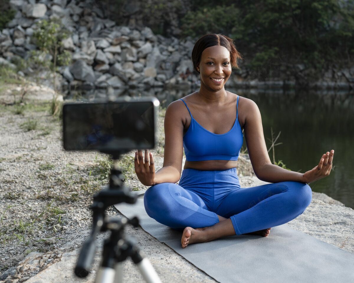 心灵非裔美国瑜伽老师在户外练习电话健康运动