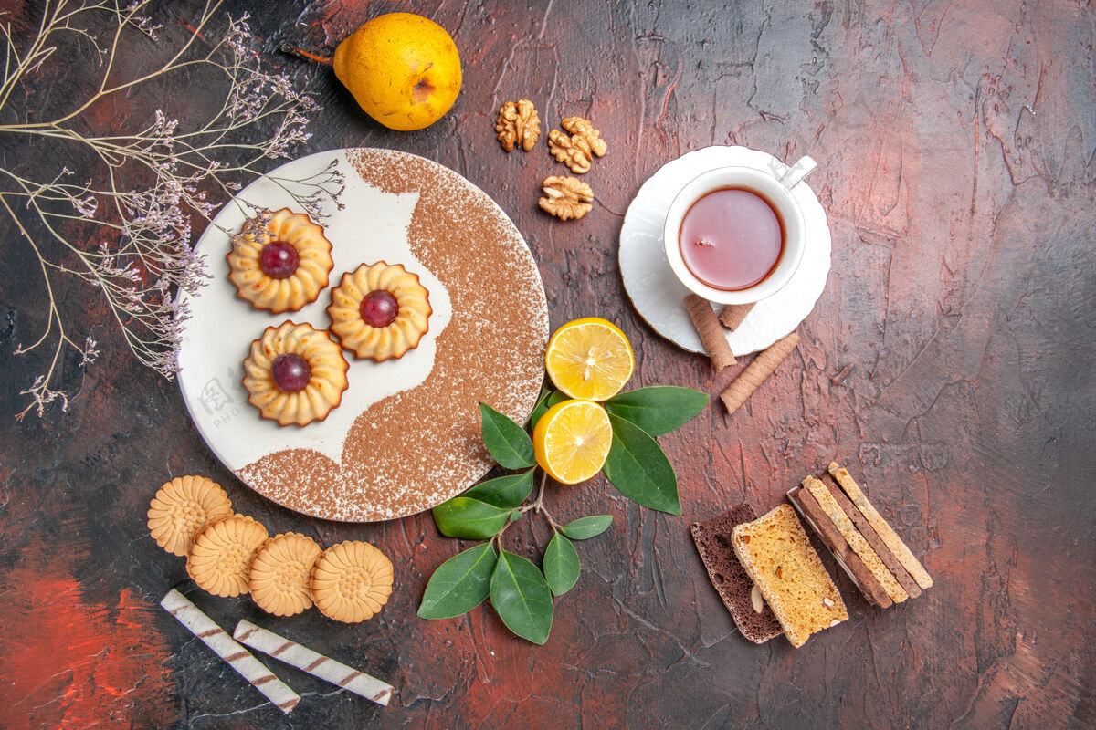 烘焙俯瞰美味的小饼干与茶杯在黑暗的桌子上糖蛋糕甜饼干茶甜点早餐