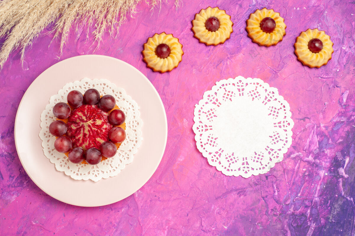 蛋糕顶视图小饼干与蛋糕在粉红色的桌子上甜甜的饼干蛋糕甜点葡萄葡萄酒饼干