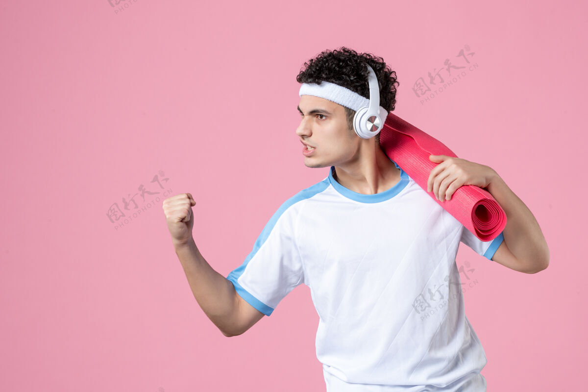 前面正面图自信的年轻男性穿着运动服 带着瑜伽垫健身房身体快乐