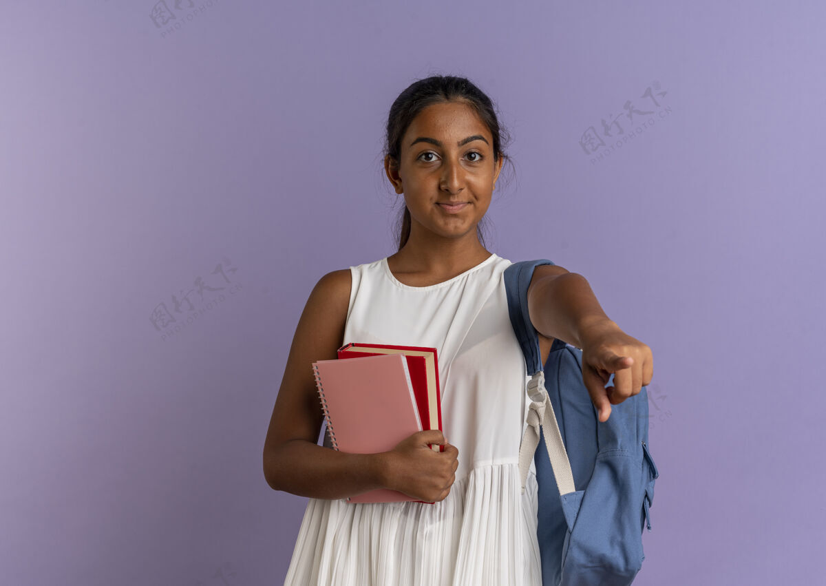 紫色高兴的小女生背着书包拿着带笔记本的书 在紫色上给你看手势手势请包