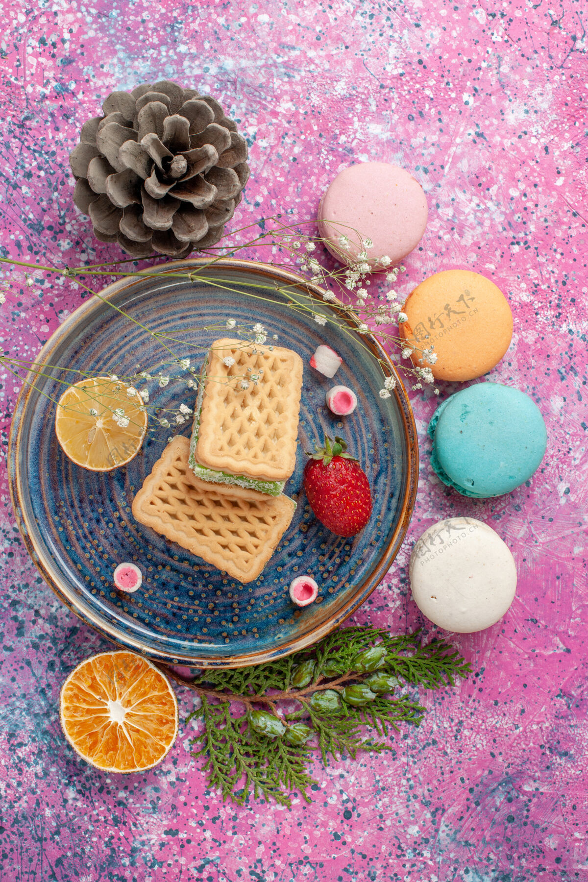 盘子粉红色桌子上美味的法式马卡龙和华夫饼的俯视图通心粉馅饼含糖