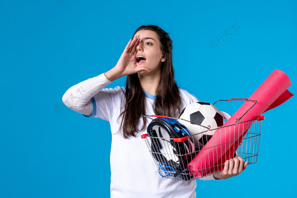 模型正面图会说话的年轻女性 带着装满运动用品的篮子前面肖像成人