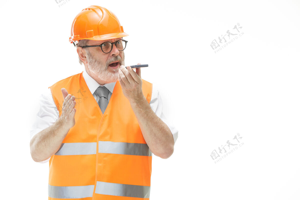 现场一个穿着建筑背心 戴着橙色头盔的建筑工人正在用手机谈论一些事情男性工人业务