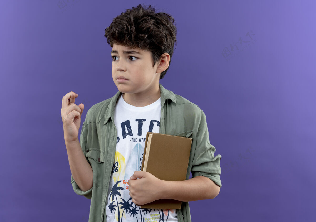 十字架看着旁边那个拿着书 交叉手指孤立在紫色墙上的关心的小男孩关心小学生手指