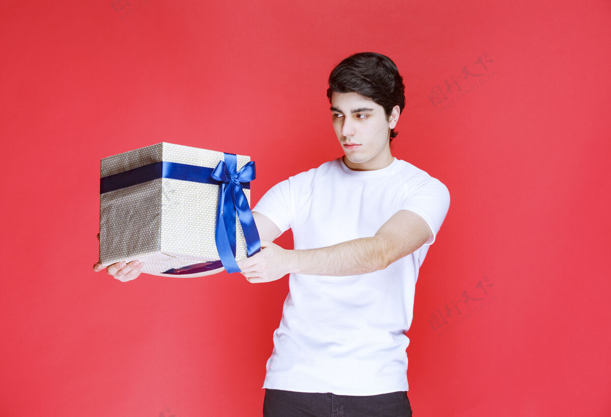 兴奋一个男人双手拿着一个包着蓝丝带的白色礼盒惊喜年轻休闲