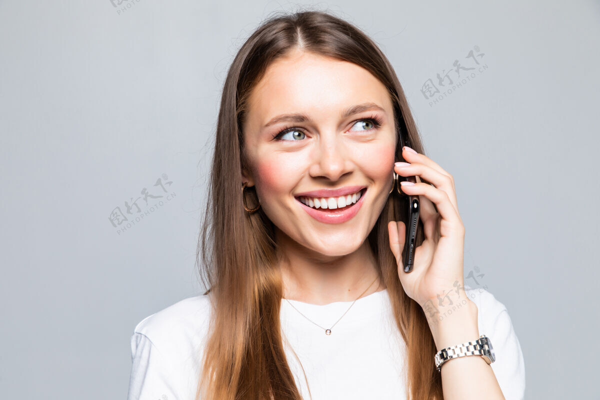 可爱微笑的女人在智能手机上说话站立人说话