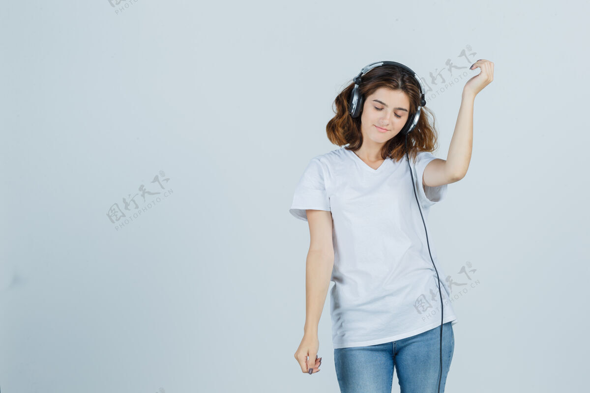 乐趣穿着白色t恤 牛仔裤的年轻女性 戴着耳机欣赏音乐 看起来很活泼 正面视图肖像漂亮护理