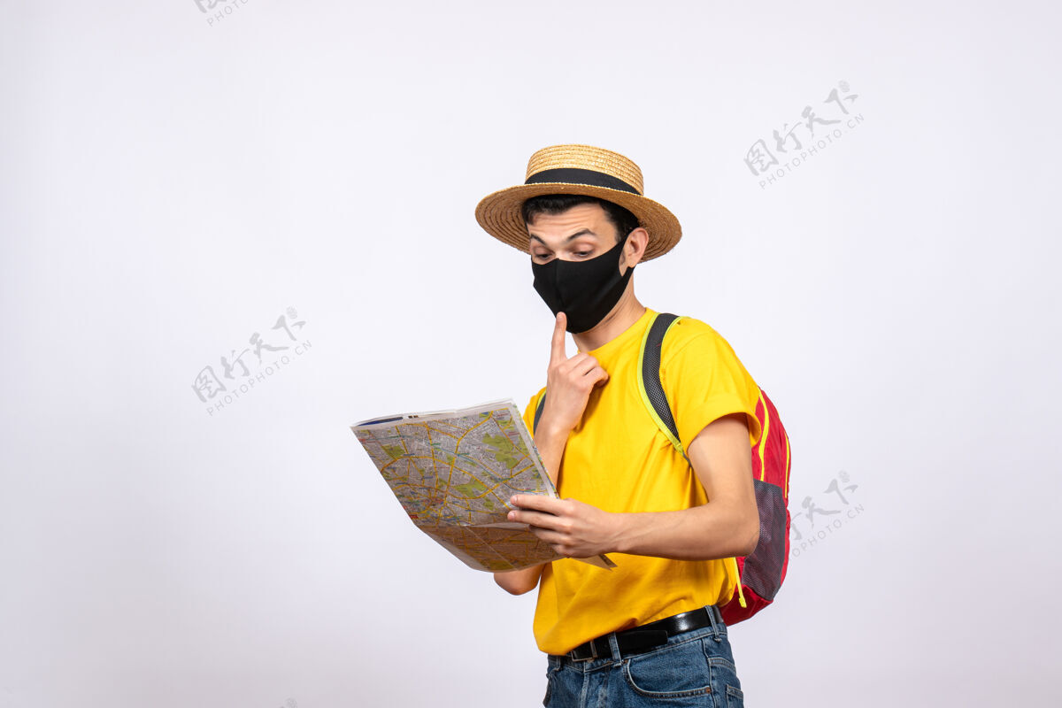 成人前视图迷惑了戴着面具和红色背包的年轻人在看地图职业背包工人