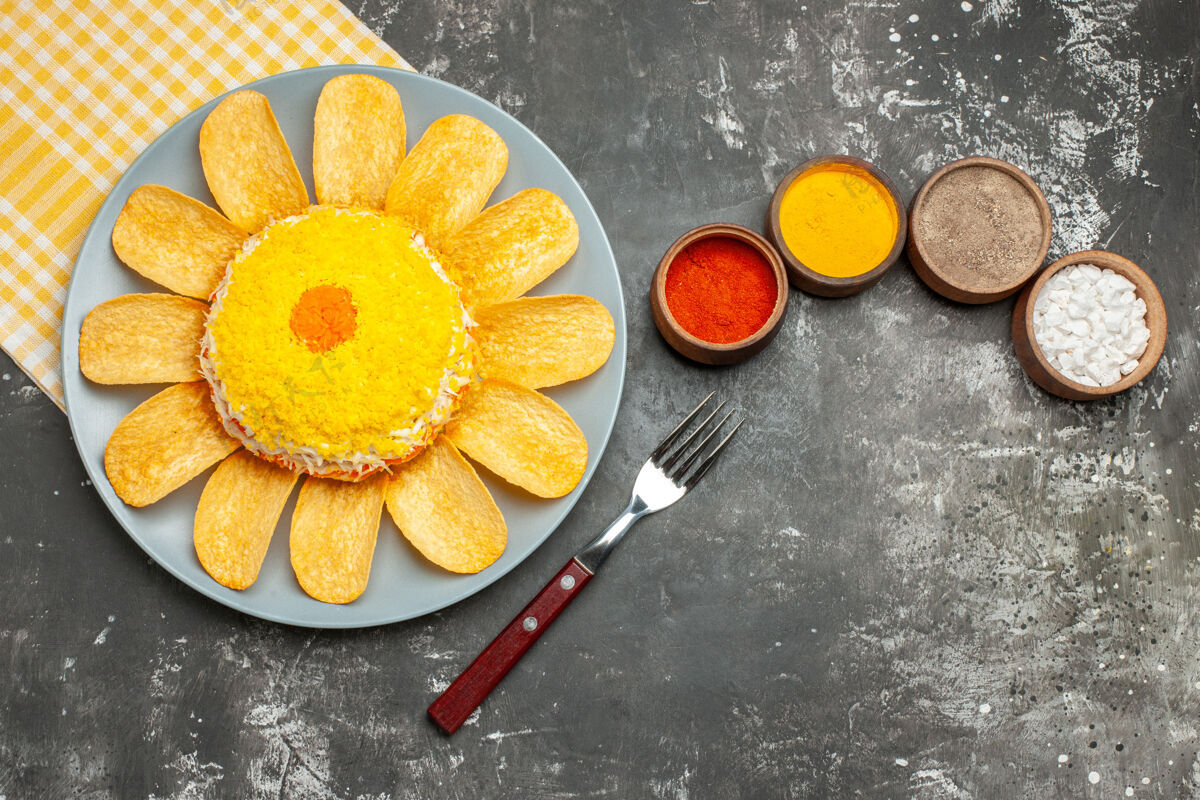 叉子沙拉的俯视图在左边 黄色的餐巾在它下面 药草和叉子在深灰色的桌子上沙拉饮食早餐