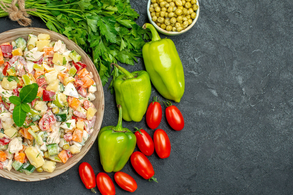 西红柿一碗蔬菜沙拉的顶视图 一边是蔬菜 在深灰色背景上为您的文本留出自由空间胡椒健康饮食