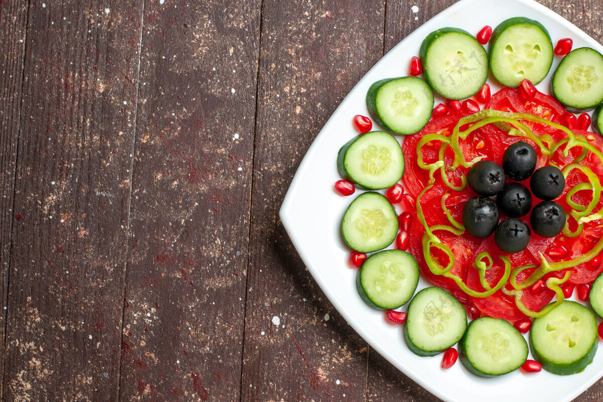 生的顶视图切片黄瓜和橄榄在一个棕色的乡村办公桌上盘子里饮食沙拉蔬菜维生素健康午餐顶部风景