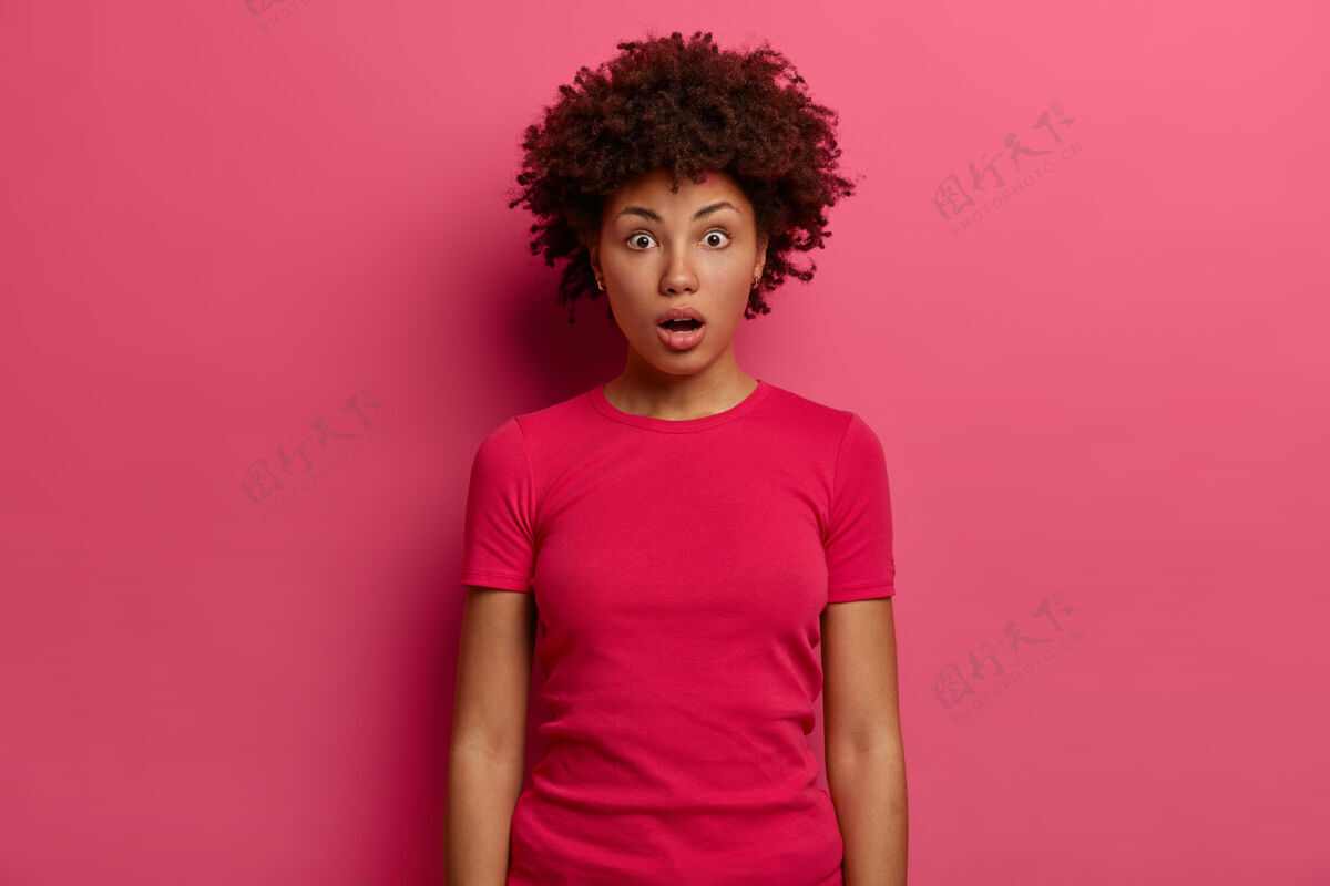哇无言震惊的女人吓得喘不过气来 意识到她到机场时忘了护照 站在那里惊呆了 印象深刻 穿着休闲t恤 在粉红色的墙上摆姿势 凝视着非洲惊讶青少年