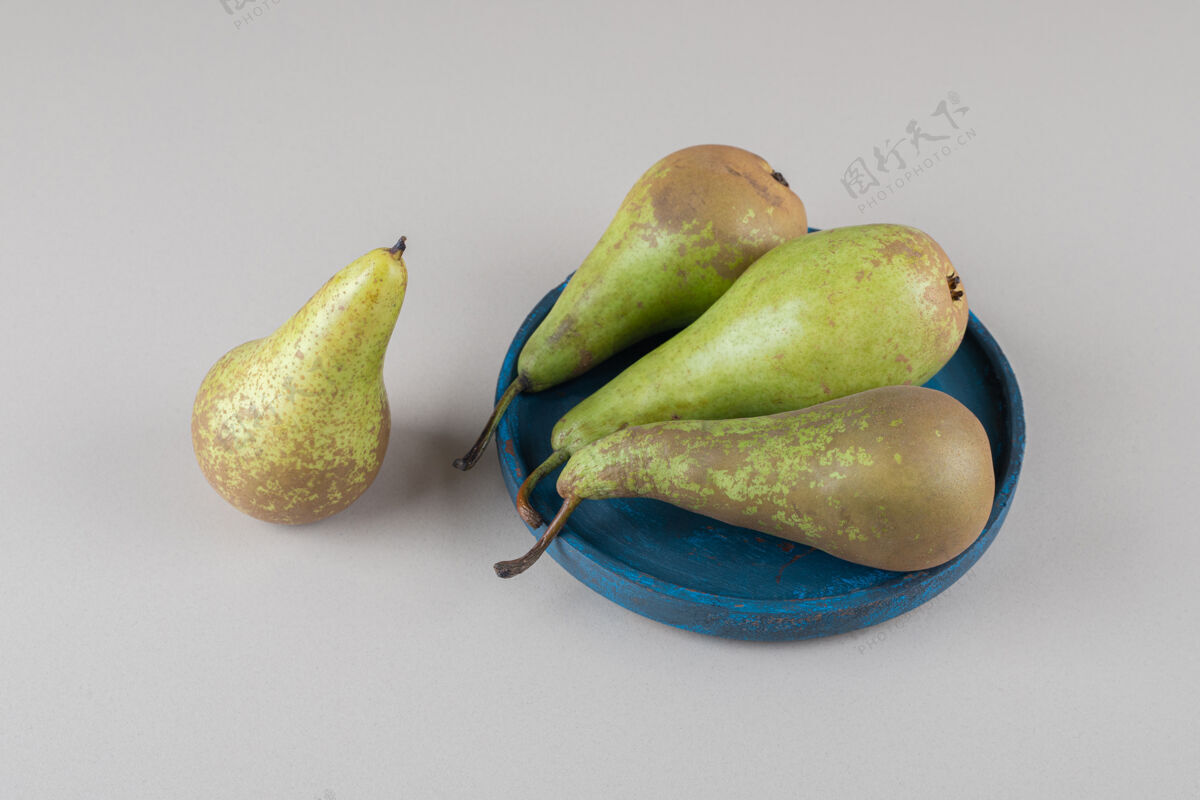 包一个梨挨着一捆梨放在大理石盘子上梨美味新鲜