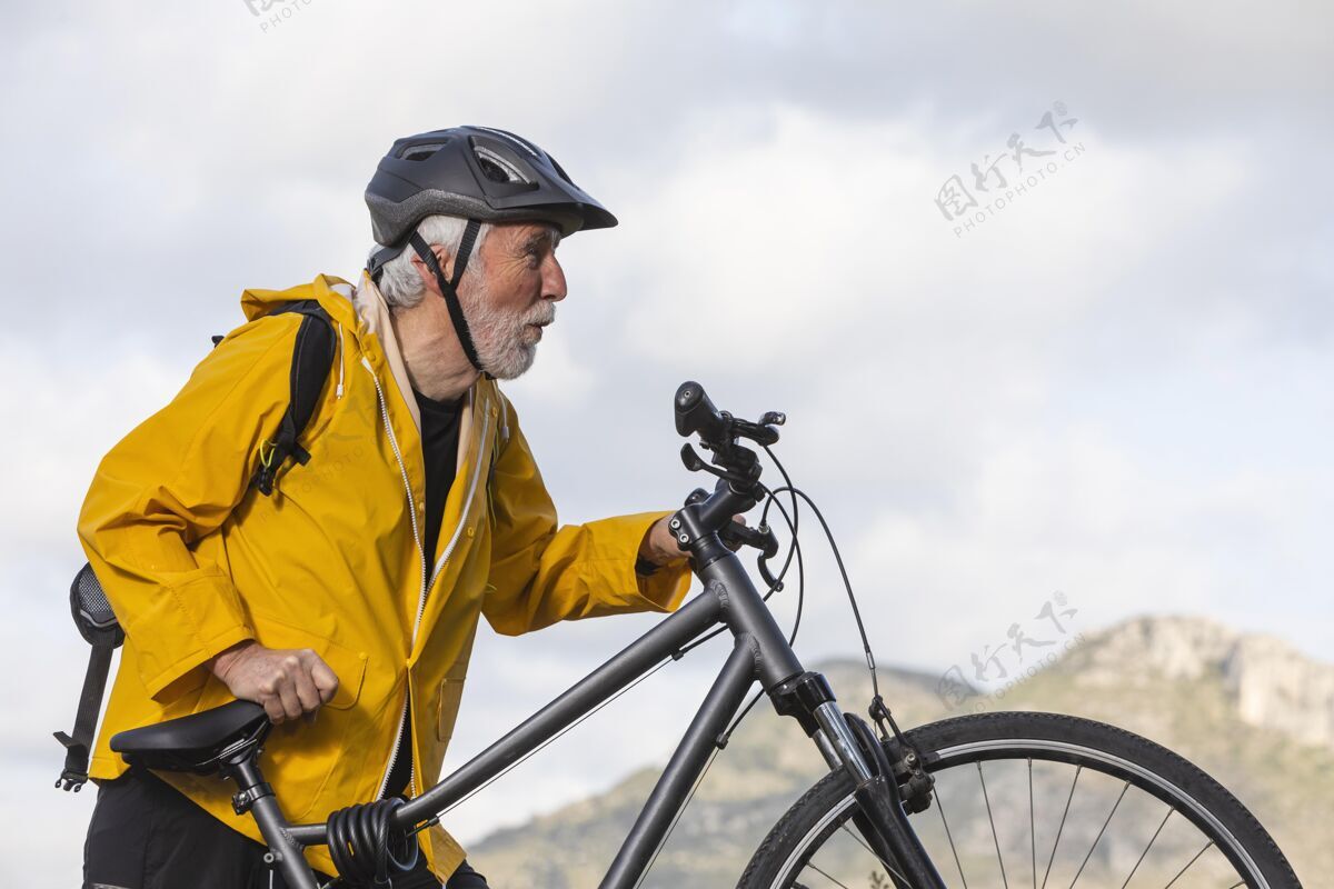 活动山上骑自行车的老人画像山头盔男性