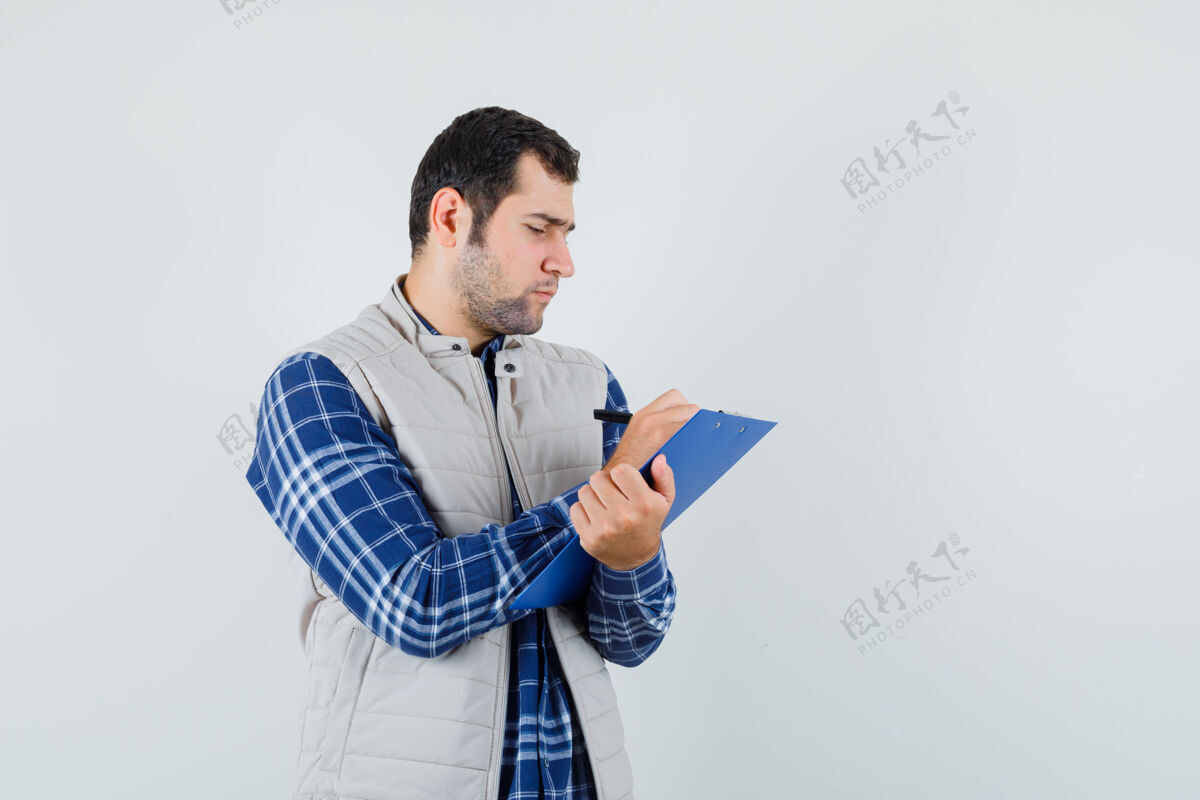幼儿穿着衬衫 夹克衫的年轻男子注意到纸上的东西 看上去很专注男孩衬衫男孩