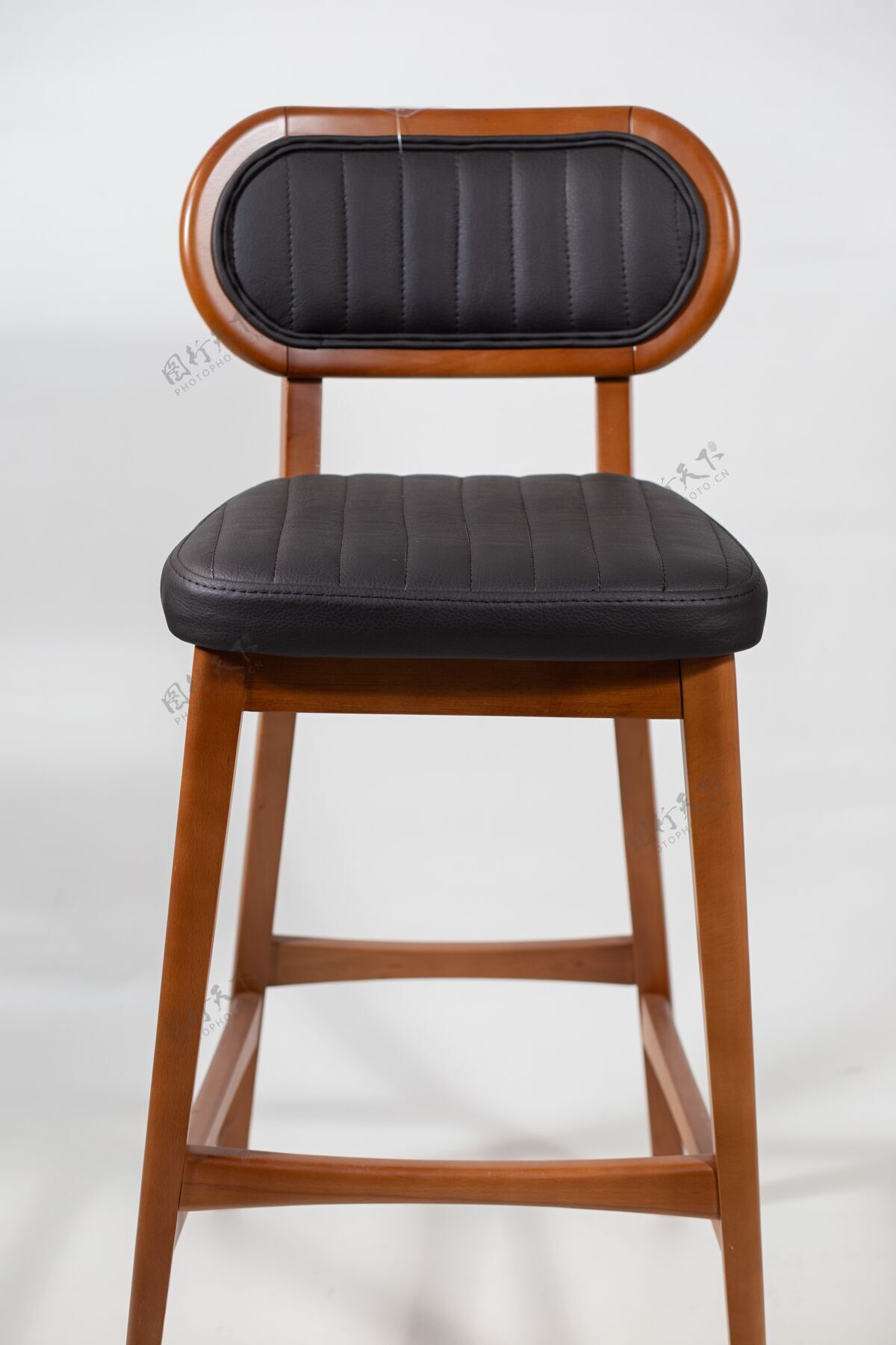 表面木椅上有一个黑色的皮革座椅隔离在一个白色的室内软硬木