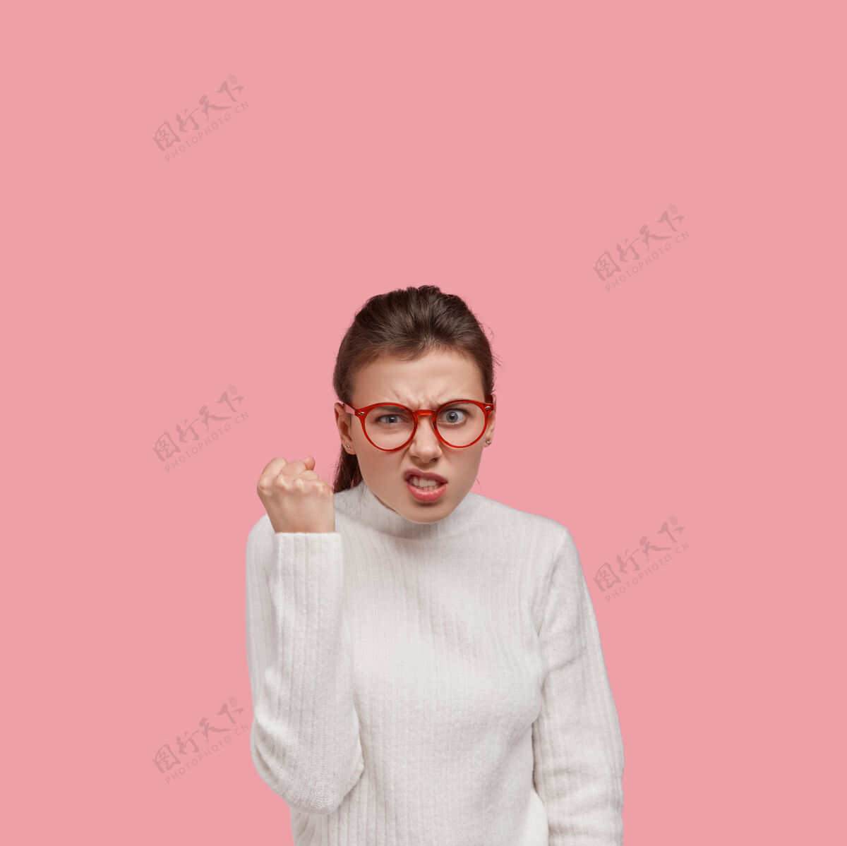 愤怒年轻的黑发女人穿着白毛衣 戴着红眼镜人年轻肖像