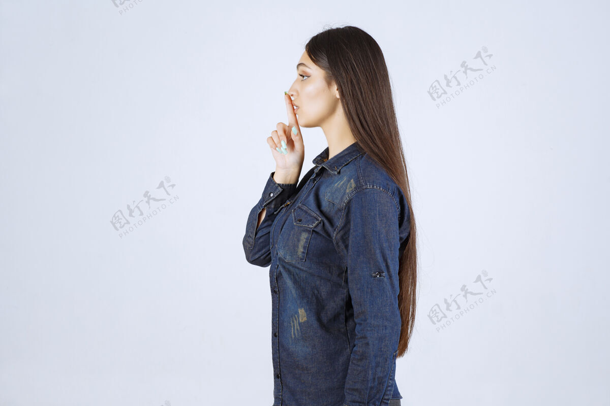 安静穿着牛仔衫的年轻女子指着自己的嘴 要求安静成人女人人