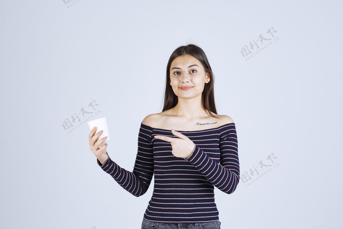 职员穿着条纹衬衫的女孩拿着一个塑料咖啡杯 介绍它是一种产品营销年轻人人类