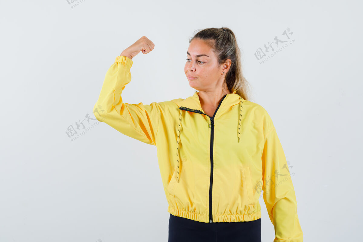 肖像穿着黄色雨衣的年轻女子露出手臂肌肉 看上去很自信人快乐脸