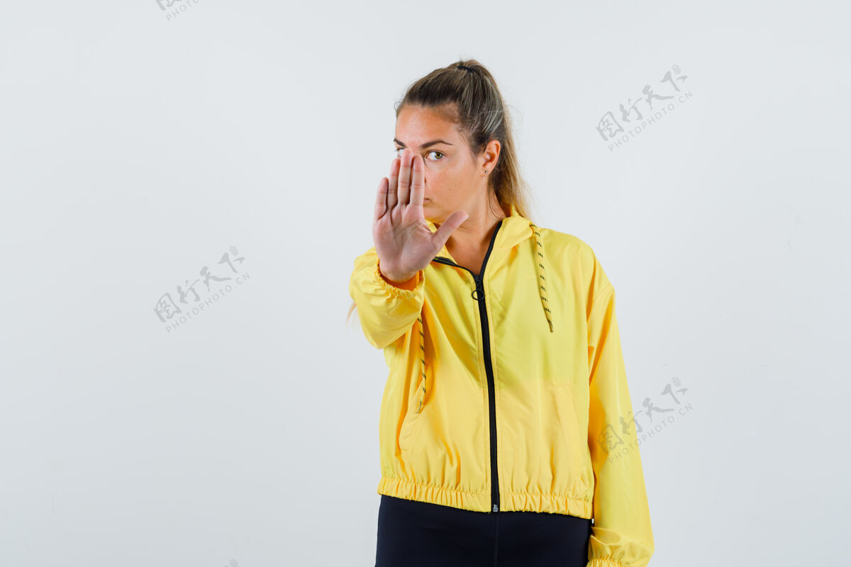 休闲一个穿着黄色雨衣 表情严肃的年轻女子在做停车手势成人前面人
