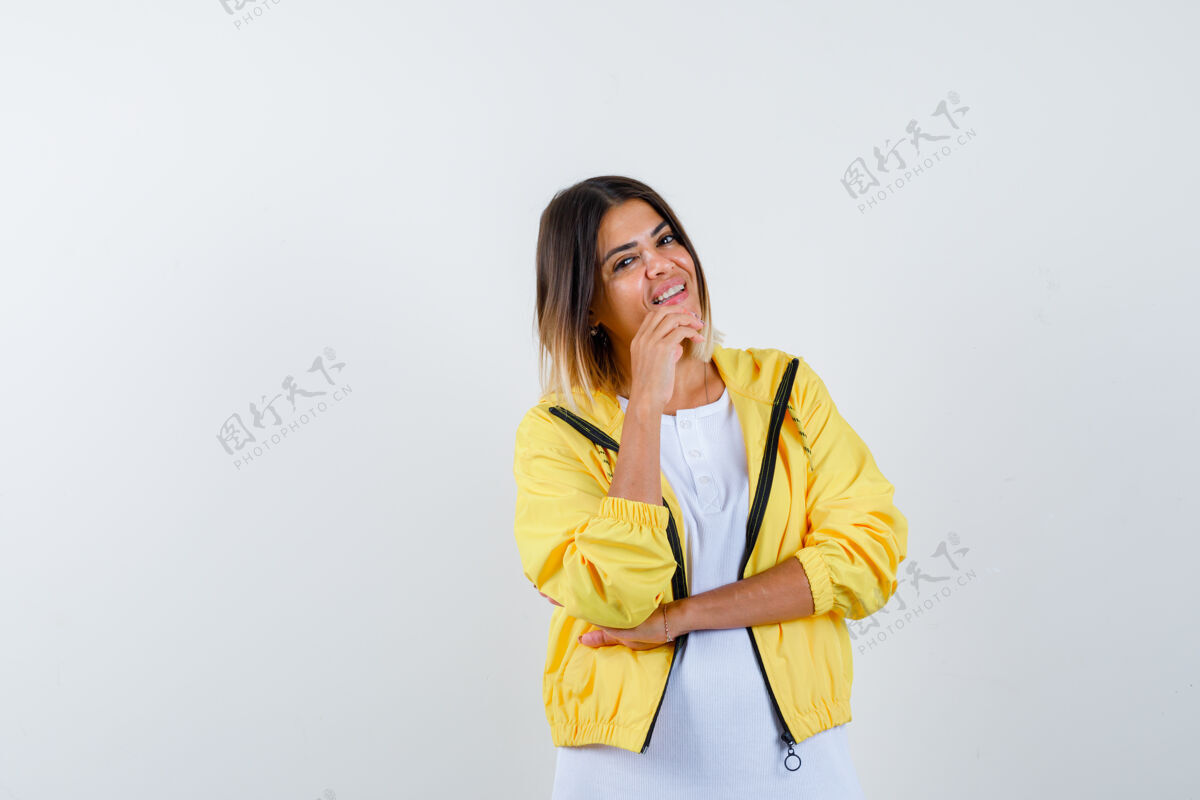 快乐穿着白色t恤 黄色夹克的年轻女孩斜靠着下巴 看上去很欢快正面图微笑女性护理