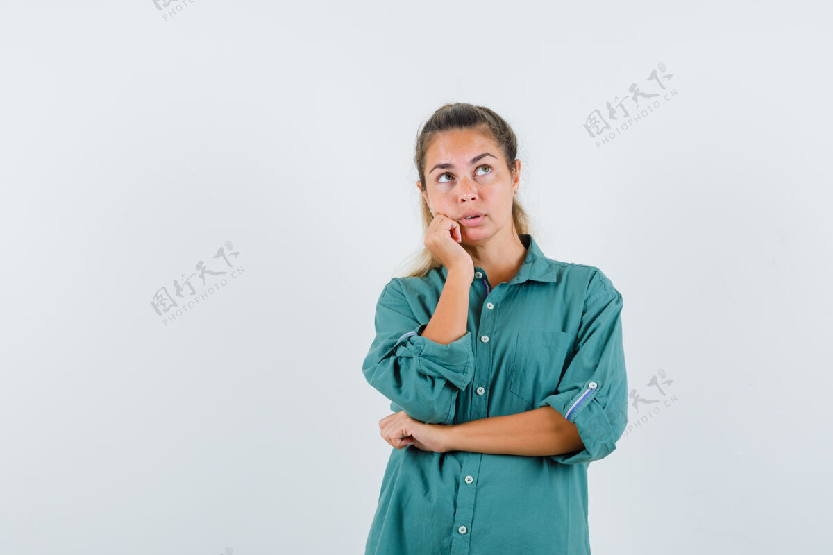 衬衫年轻的女人一边看一边斜倚在她穿着蓝色衬衫的手上 显得若有所思眼睛休闲前面