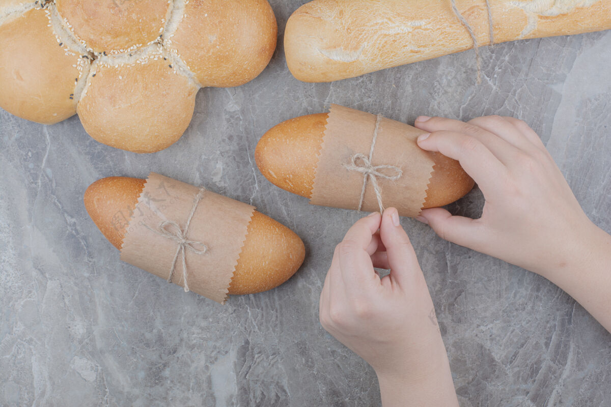 面包手拿着一个小面包放在大理石表面长食品脆