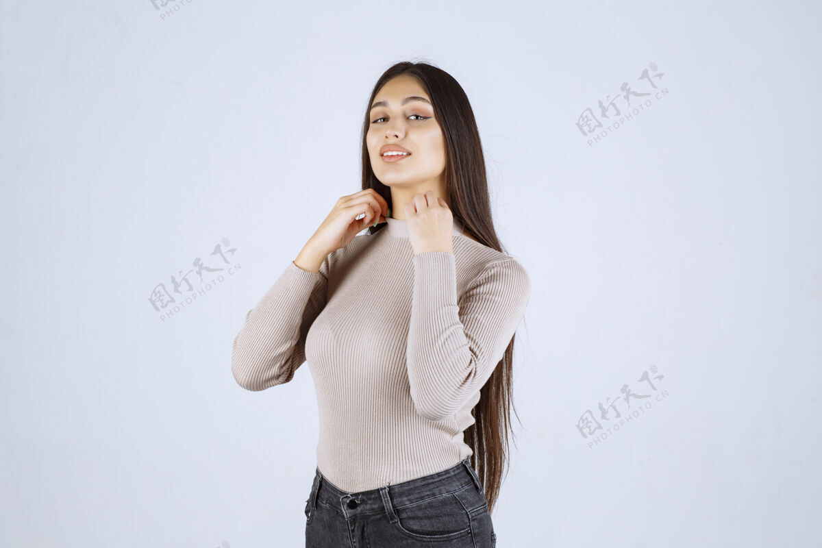 年轻穿灰色衬衫的女孩摆出积极而吸引人的姿势姿势邀请人体模特