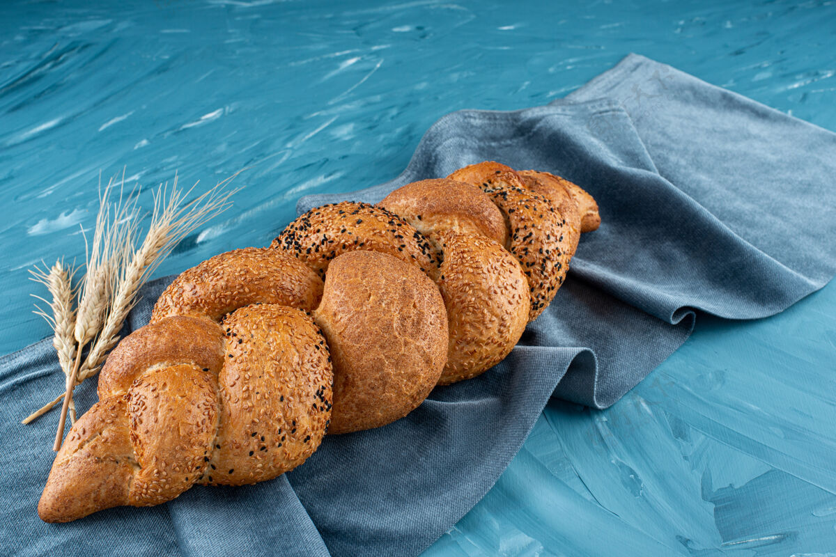 美味刚出炉的编织面包 放在深色桌布上谷物形状餐巾纸