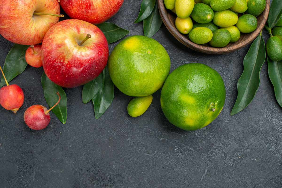 食物顶部特写查看柑橘类水果苹果樱桃柑桔一碗带叶子的柑橘类水果苹果吃苹果健康