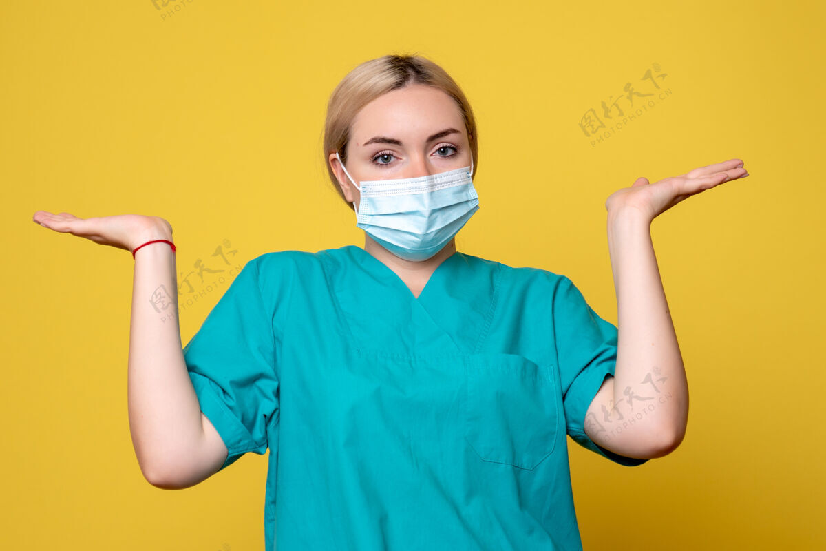 脸黄色墙壁上穿着医用衬衫和无菌口罩的年轻女医生的正面图年轻女医生医院消毒