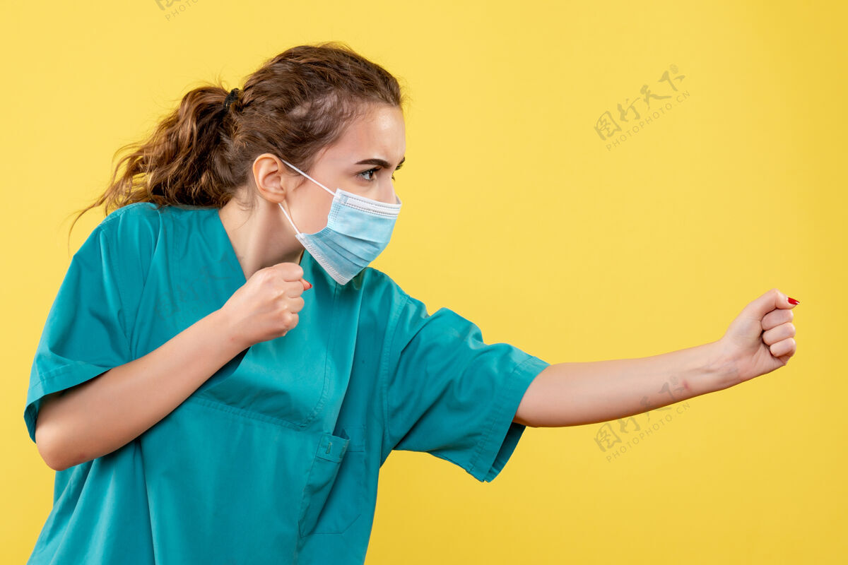 年轻女医生黄色墙上穿着医用衬衫和无菌口罩的年轻女医生的正视图医疗外套人