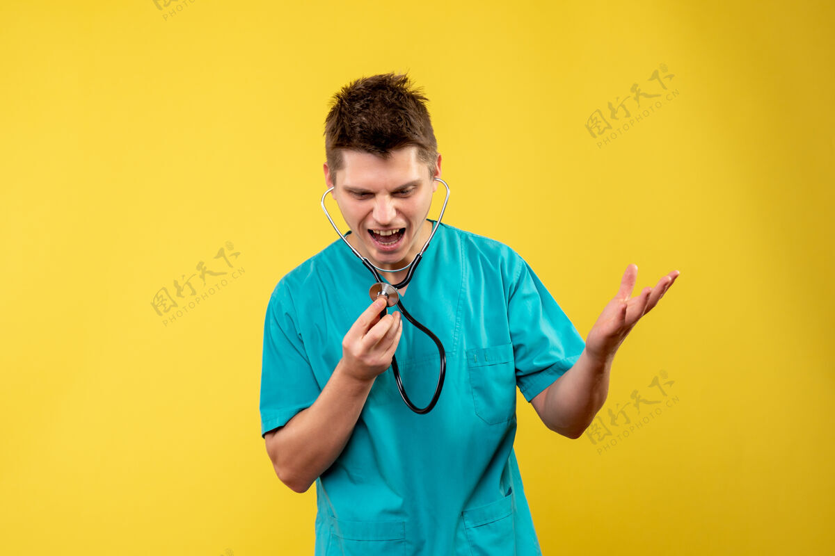 情绪黄色墙壁上穿着带听诊器的医疗服的男医生的正视图西装前面病毒