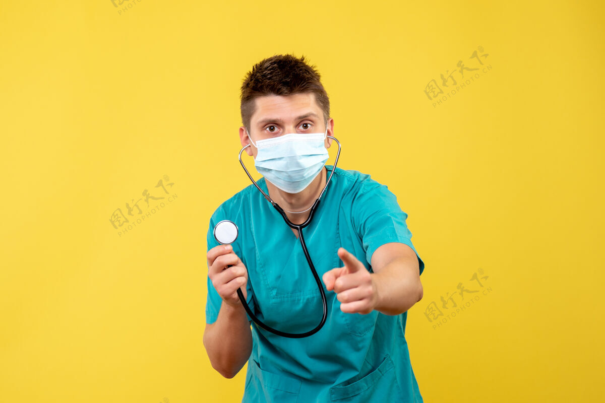 前面黄色墙壁上穿着医疗服 戴着听诊器面罩的男医生的正视图医疗套装健康