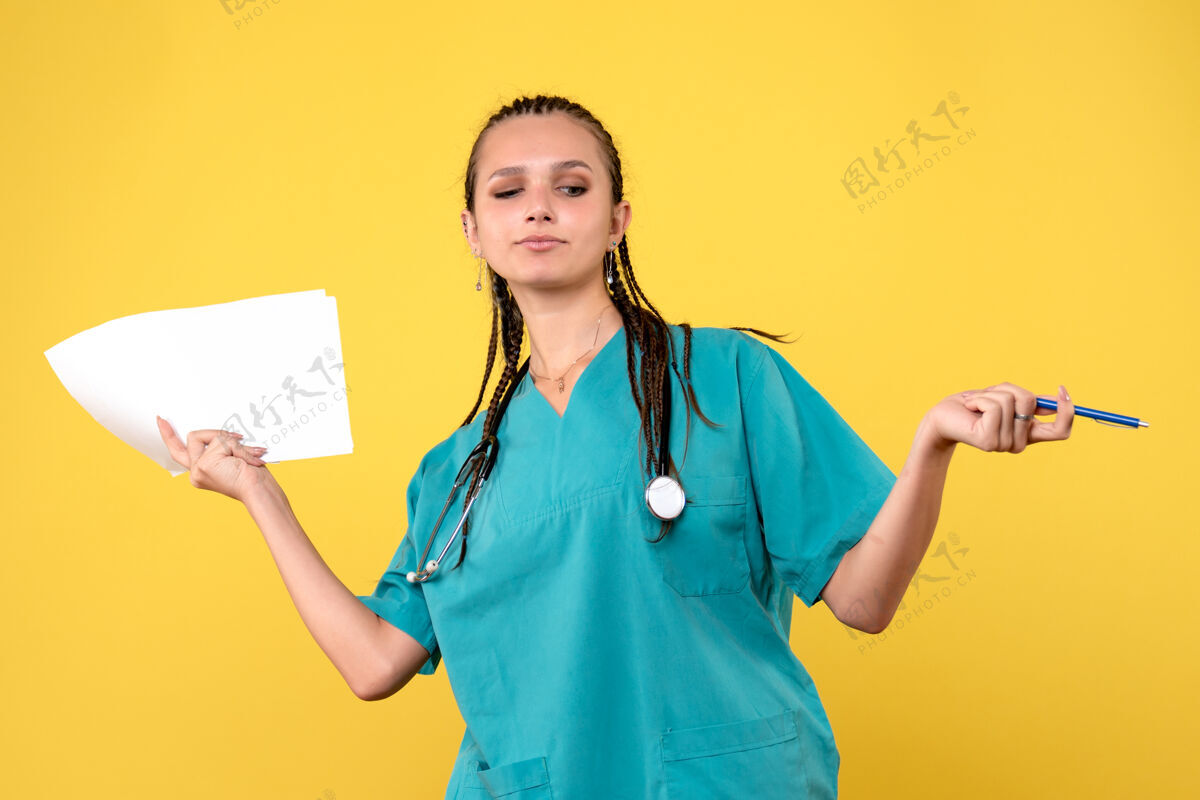 健康身着医疗服的女医生的正面图 黄色的墙上有纸纸张医疗病毒