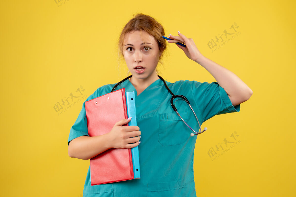 护士黄色墙壁上的女医生穿着医疗服 带着论文和分析的正视图纸张分析人