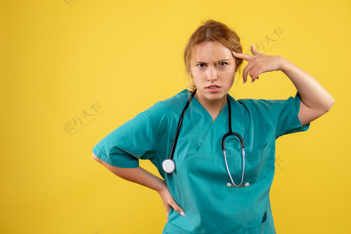 医生黄色墙壁上穿着带听诊器的医疗服的女医生的正视图西装医疗仪器