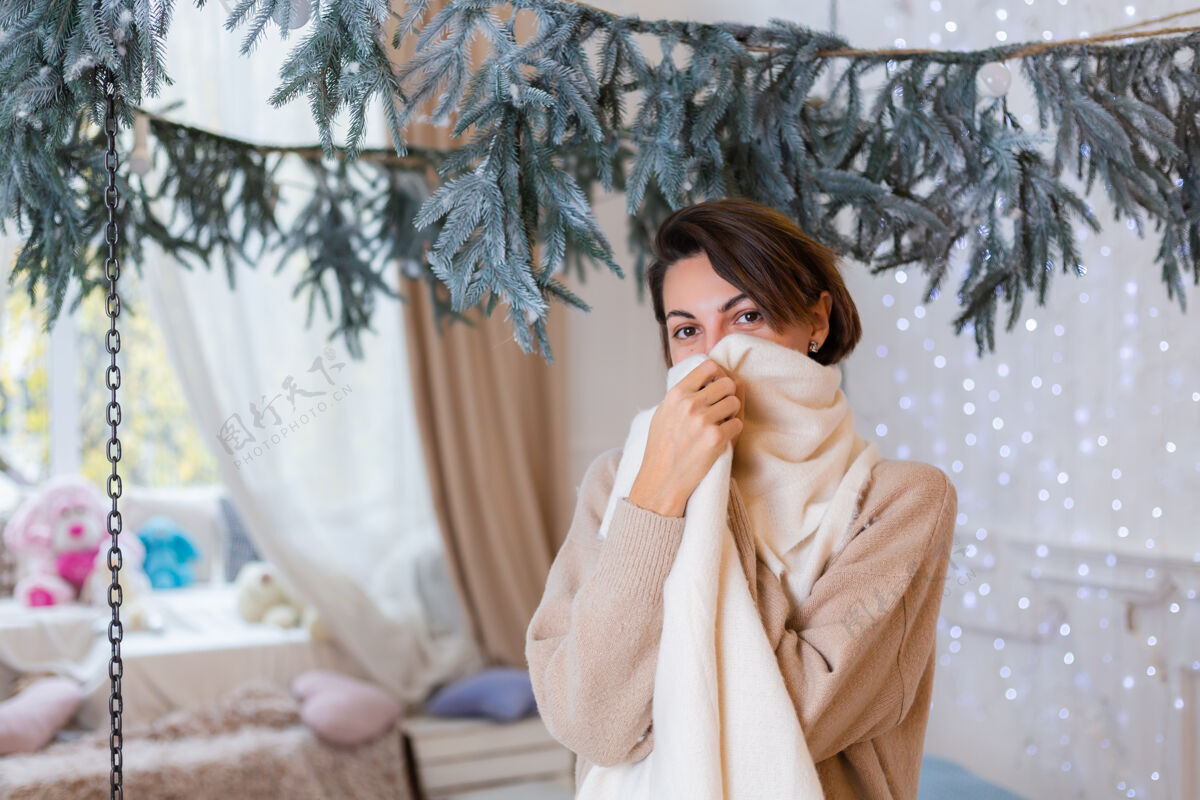 针织穿着毛衣 牛仔裤和白围巾的快乐女人在卧室的温馨写真卧室圣诞节袜子