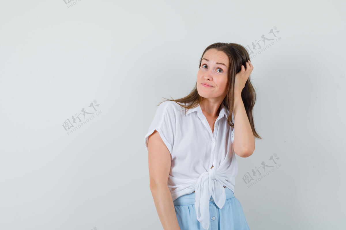 脸一个穿着白衬衫和浅蓝色裙子的年轻女人搔首弄姿 看上去很高兴自然新鲜美丽